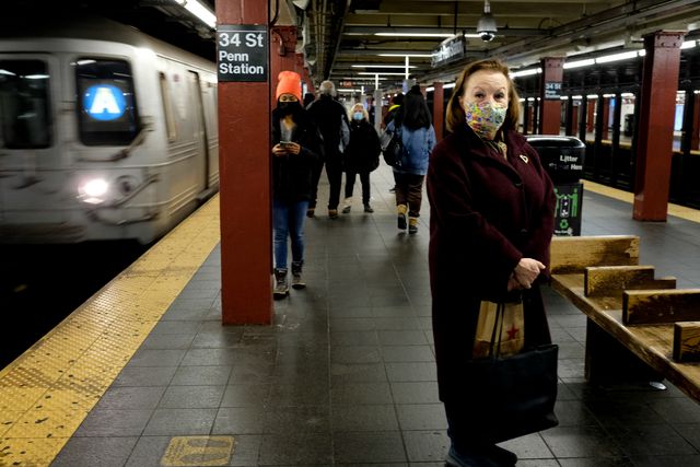 A woman poses for a photo on a subway platform.